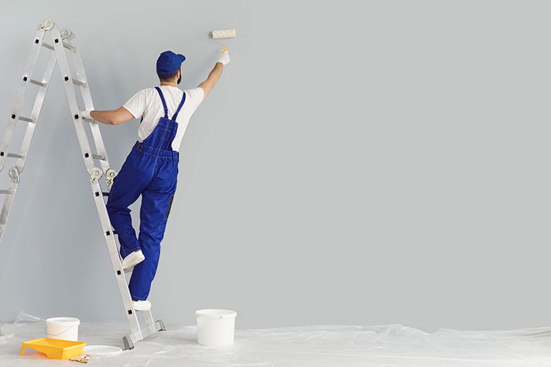 Painter in blue painting walls